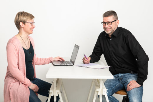 Kaksi henkilöä on neuvottelussa pöydän ääressä.