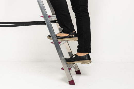 Henkilö nousee tikkaita ylöspäin, vain jalat näkyvät.
