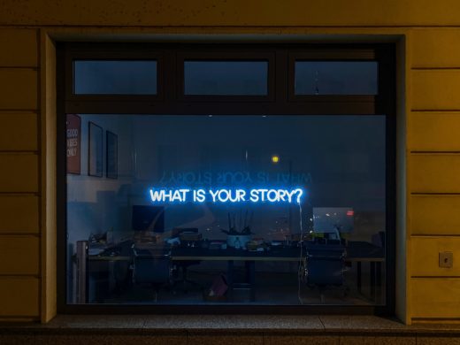 Ikkunassa valoteksti "What is your story?"