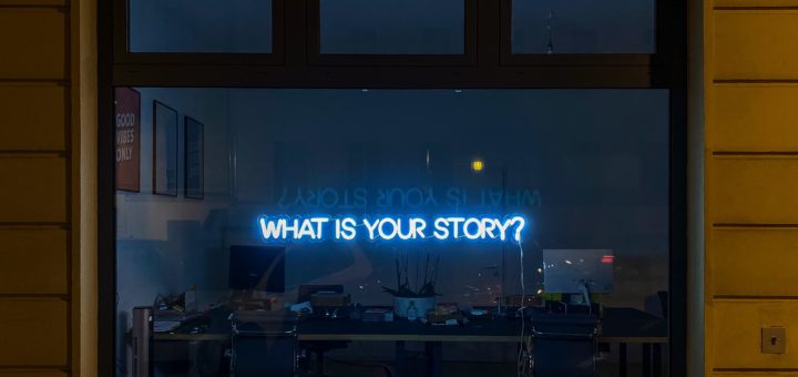 Ikkunassa valoteksti "What is your story?"