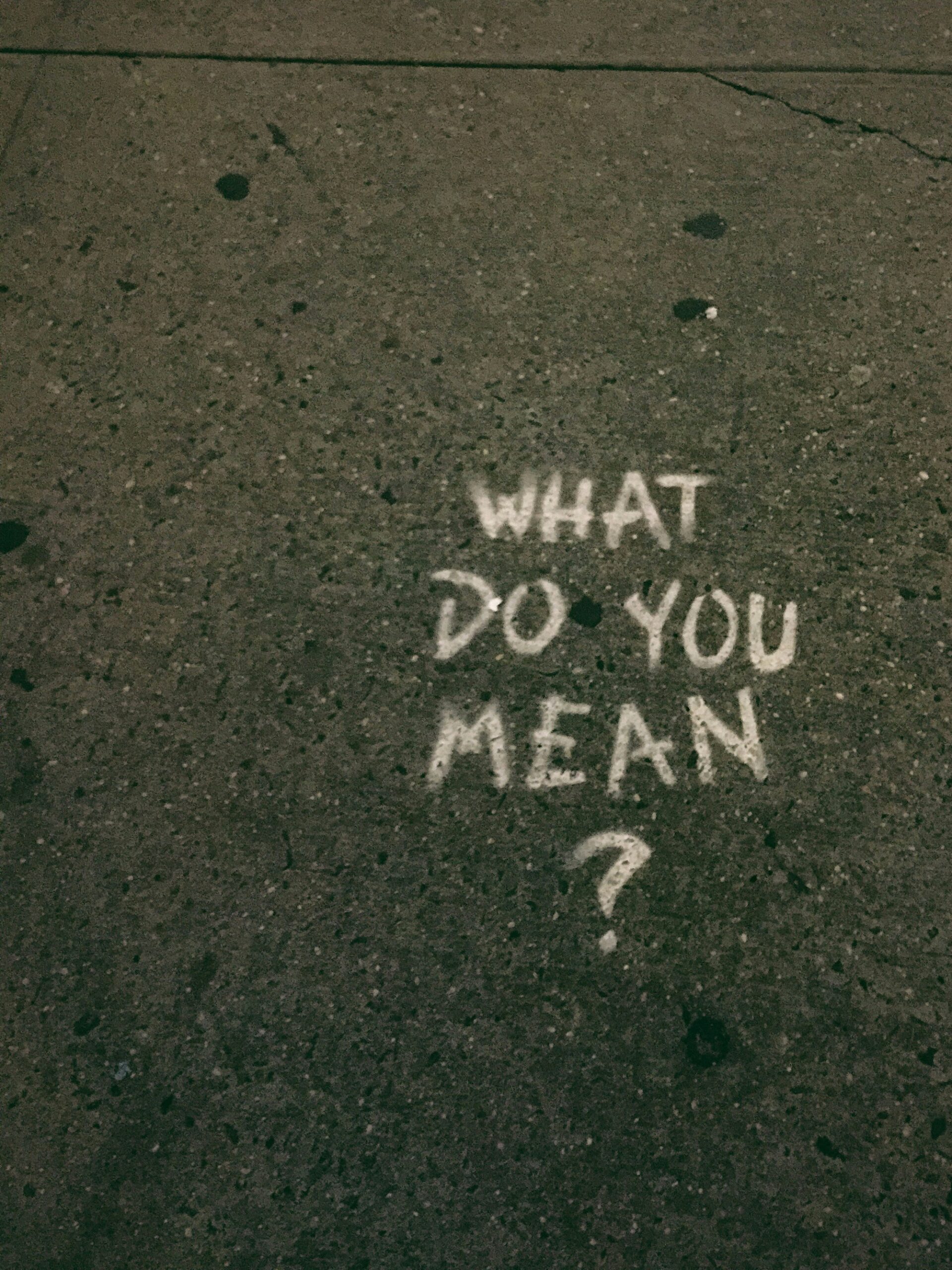 Teksti "What dou you mean" kirjoitettu valkoisella maahan.